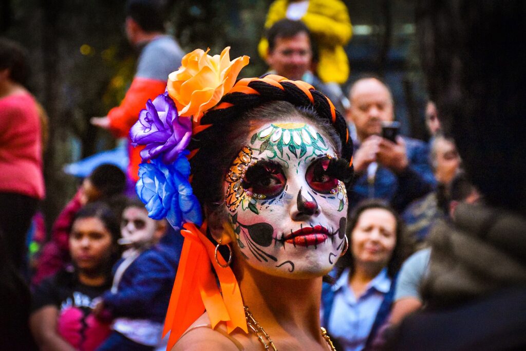 Mujer caracterizada de catrina con flores en el pelo durante un desfile del Día de Muertos